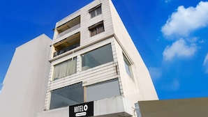 A hotel with a modern facade, a visible sign indicating it is a company-serviced hotel, and a clear blue sky in the background. - Classic With View Mivaan Comfort (Barasat)