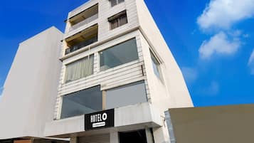 A hotel with a modern facade, a visible sign indicating it is a company-serviced hotel, and a clear blue sky in the background.