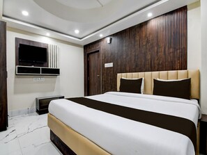 A modern bedroom with a large bed, a flat-screen TV mounted on the wall, and a wooden panel design on the wall behind the bed. - Classic With View Mivaan Comfort (Barasat)
