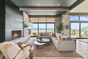 Una sala moderna con chimenea, ventanas amplias y vistas al exterior.