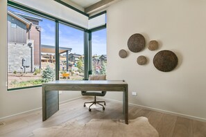 Una habitación con un ventanal grande, un escritorio y placas decorativas en la pared.