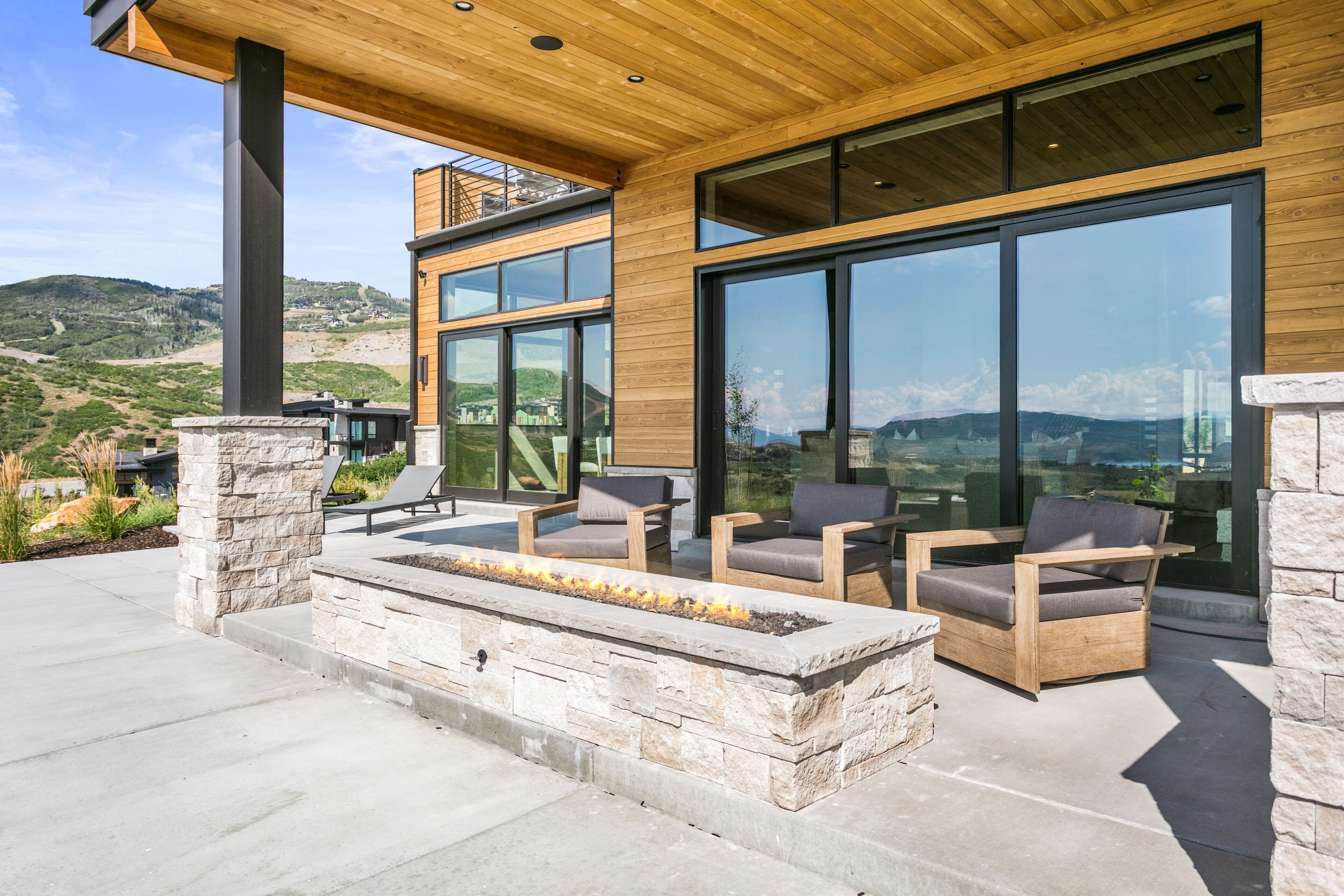 A modern outdoor seating area with stone walls and a fire feature.