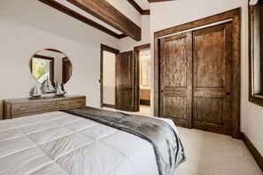 Een slaapkamer met een groot bed, een houten garderobe en een spiegel.