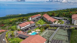 A resort with multiple buildings, a swimming pool, tennis courts, and solar panels. - Kona Coffee Villas F153 2 Bedroom Condo (Holualoa)