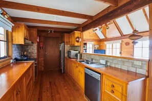 Een houten keuken met een koelkast, fornuis en spoelbak.