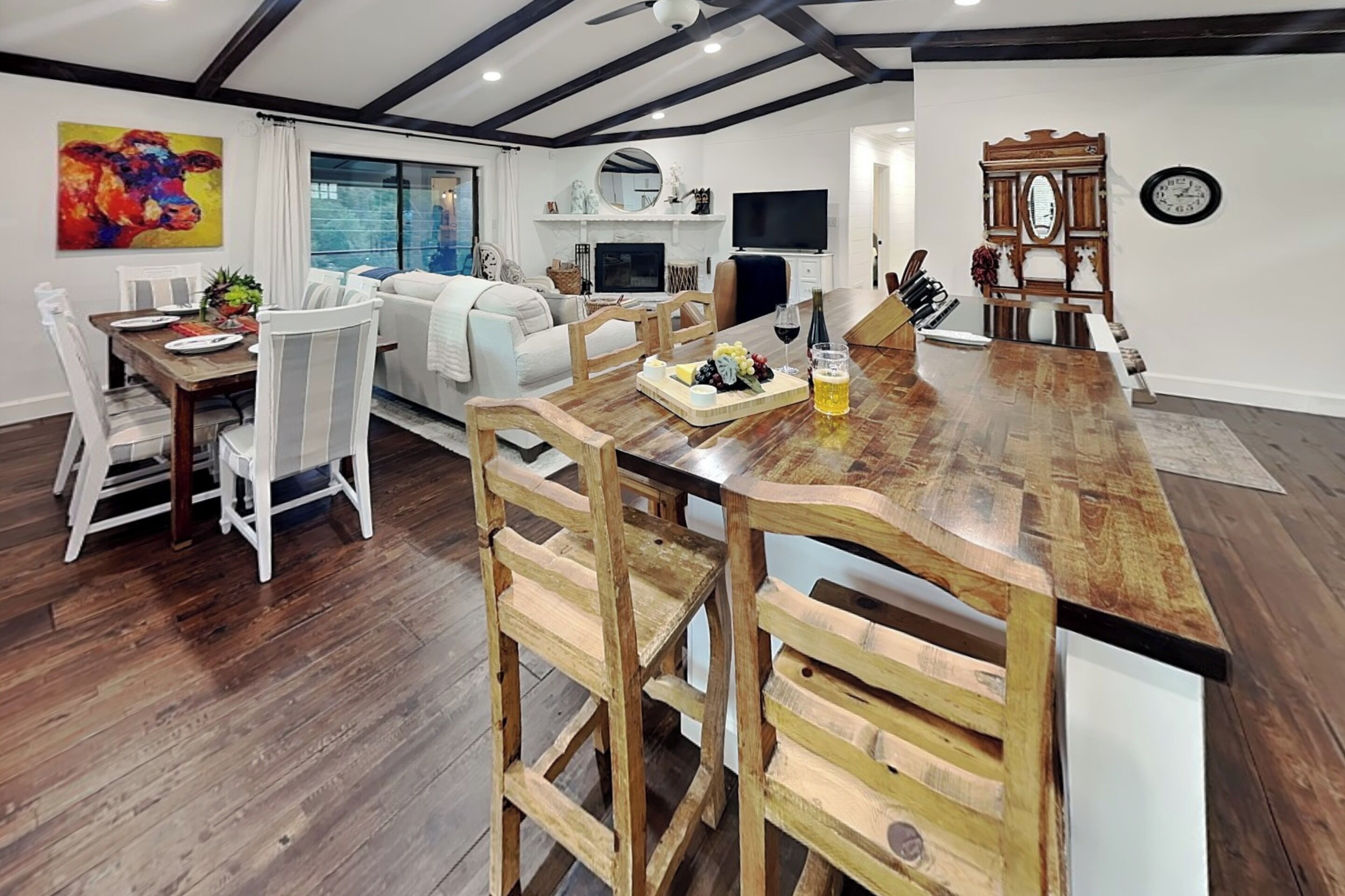 Une cuisine moderne avec un îlot central en bois, des meubles blancs et un coin repas avec des chaises blanches.