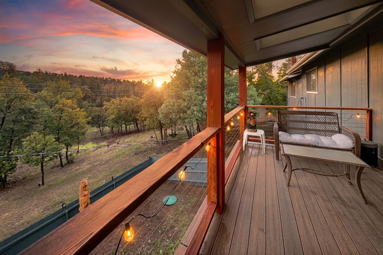 Eine Holzterrasse mit einer Bank und einem Tisch mit Blick auf ein bewaldetes Gebiet.