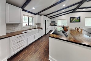 A modern kitchen with white cabinetry, a wooden countertop, and a central island. - Amigos Nest | Updated Home, Great Views, + Fireplace (Alto)