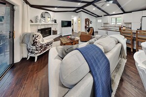 A modern living room with a fireplace, a television, and a dining area with wooden chairs. - Amigos Nest | Updated Home, Great Views, + Fireplace (Alto)
