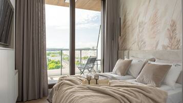 Une chambre avec un grand lit, une vue sur la ville depuis un balcon et une chaise à l’extérieur.