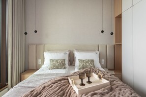 Un dormitorio moderno con una cama grande, dos almohadas, una mesita de noche y un aparador.