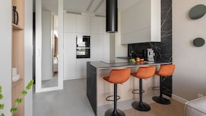 A modern kitchen with a central island, bar stools, and a black range hood. - Bulvar Penthouse Collection Gdańsk (Gdańsk)