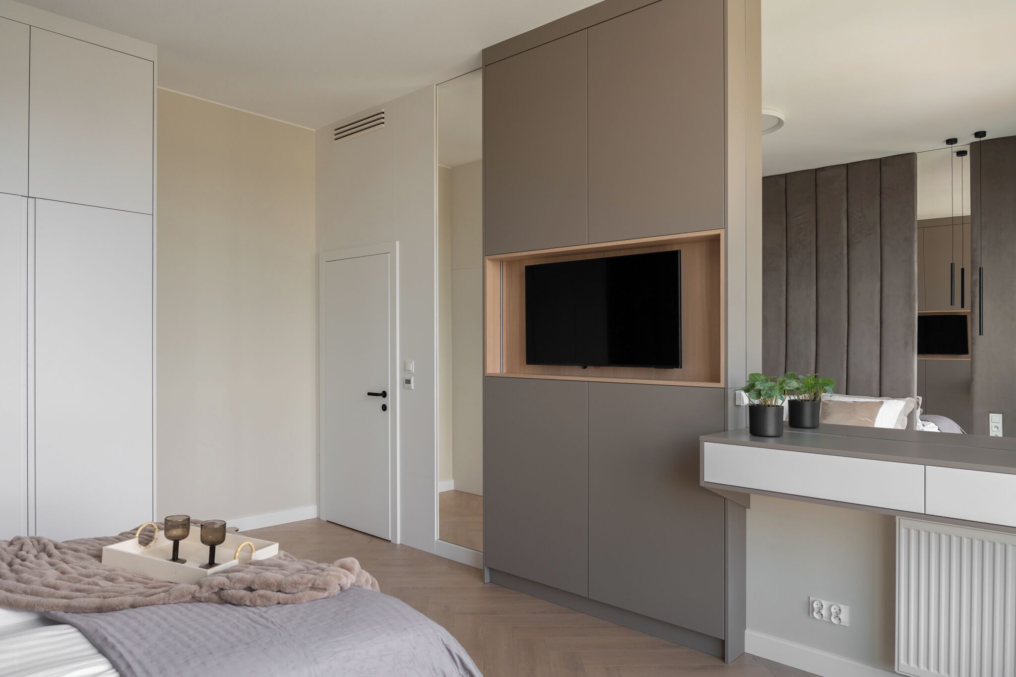 Ein Schlafzimmer mit Bett, Nachttisch und einem an der Wand befestigten Fernseher.