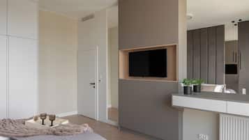 Ein Schlafzimmer mit Bett, Nachttisch und einem an der Wand befestigten Fernseher.