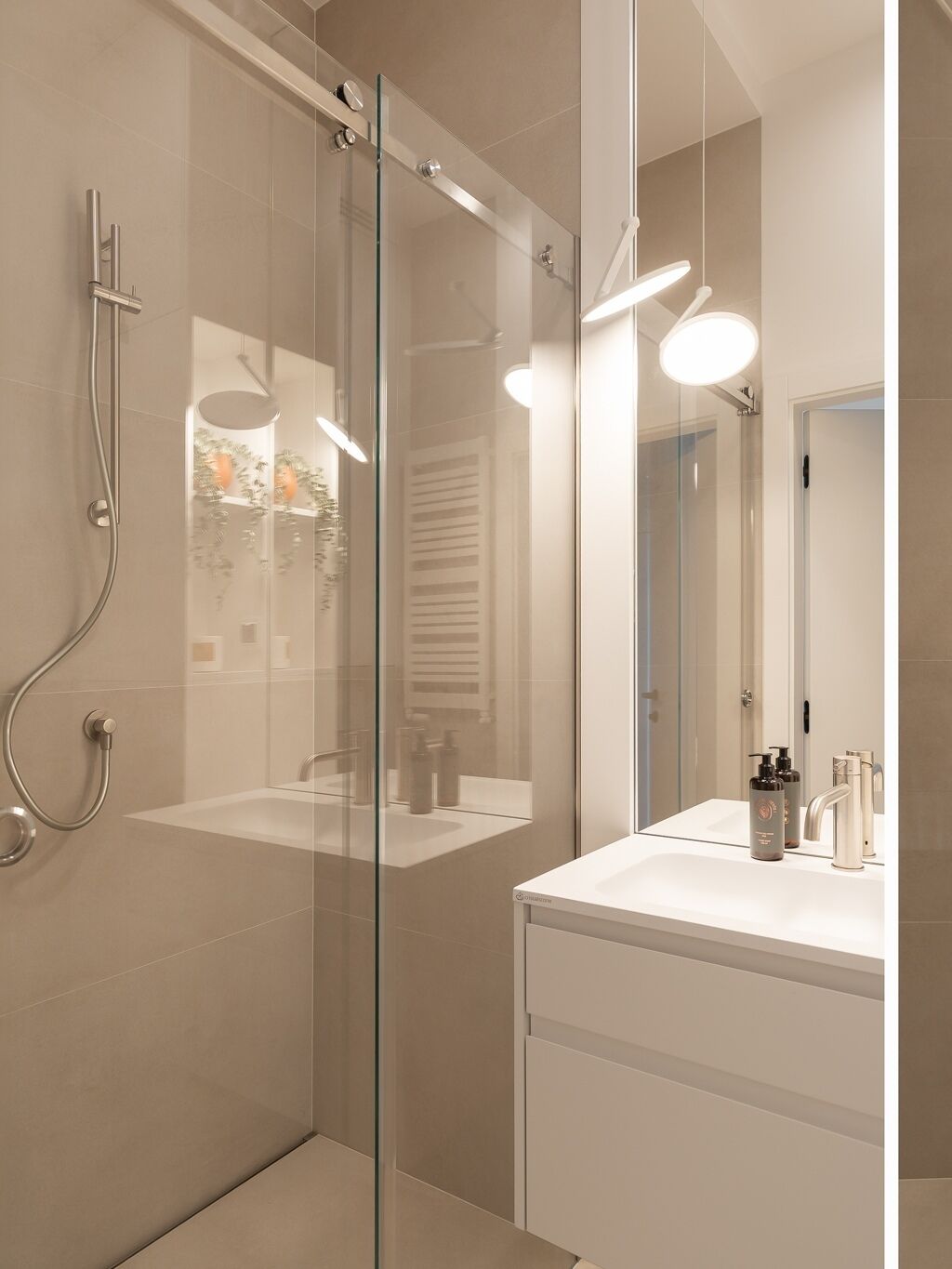 A modern bathroom with a glass-enclosed shower, a white sink, and a mirror.