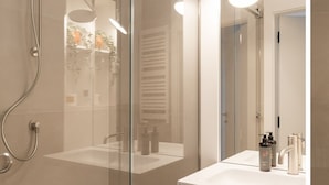 Ein modernes Badezimmer mit einer einachigen Duschkabine, einem weißen Waschbecken und einem Spiegel.