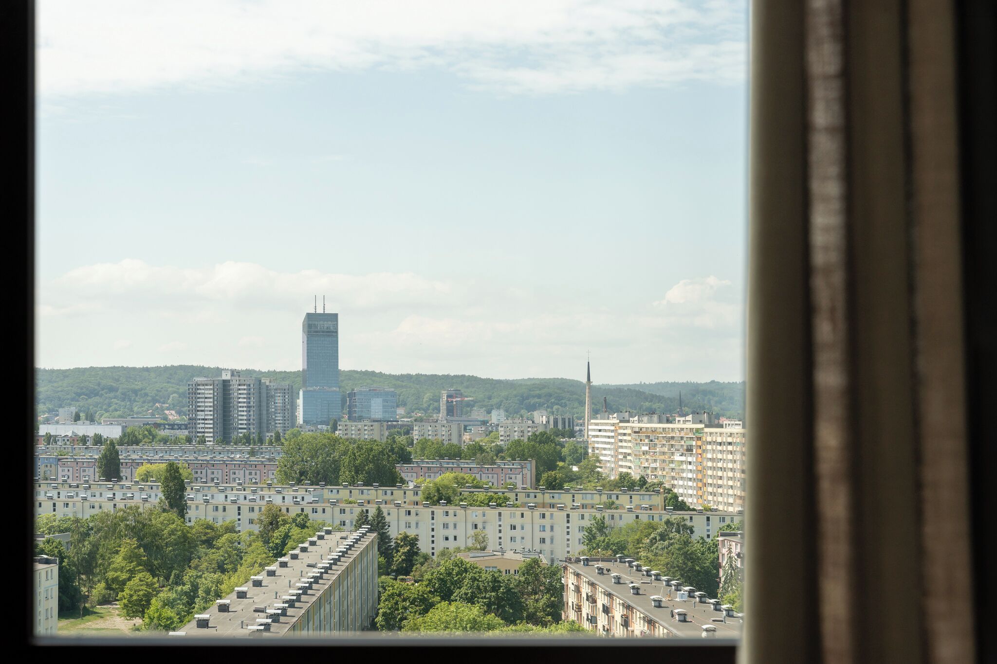 Eine Stadtansicht mit Hochhäusern, einem markanten Wolkenkratzer und Wohngebieten.