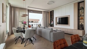 A modern living room with a sofa set, dining area, and a TV mounted on the wall. - Bulvar Penthouse Collection Gdańsk (Gdańsk)