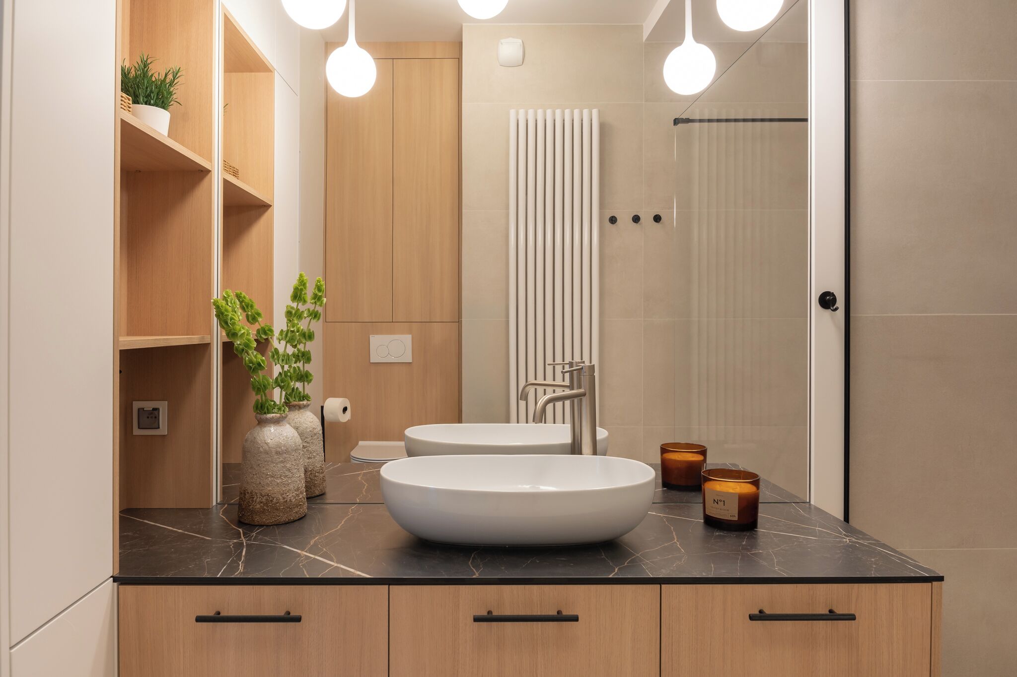 Ein modernes Badezimmer mit großem Spiegel, zwei Waschbecken, einer Handtuchstange und einer Dusche.