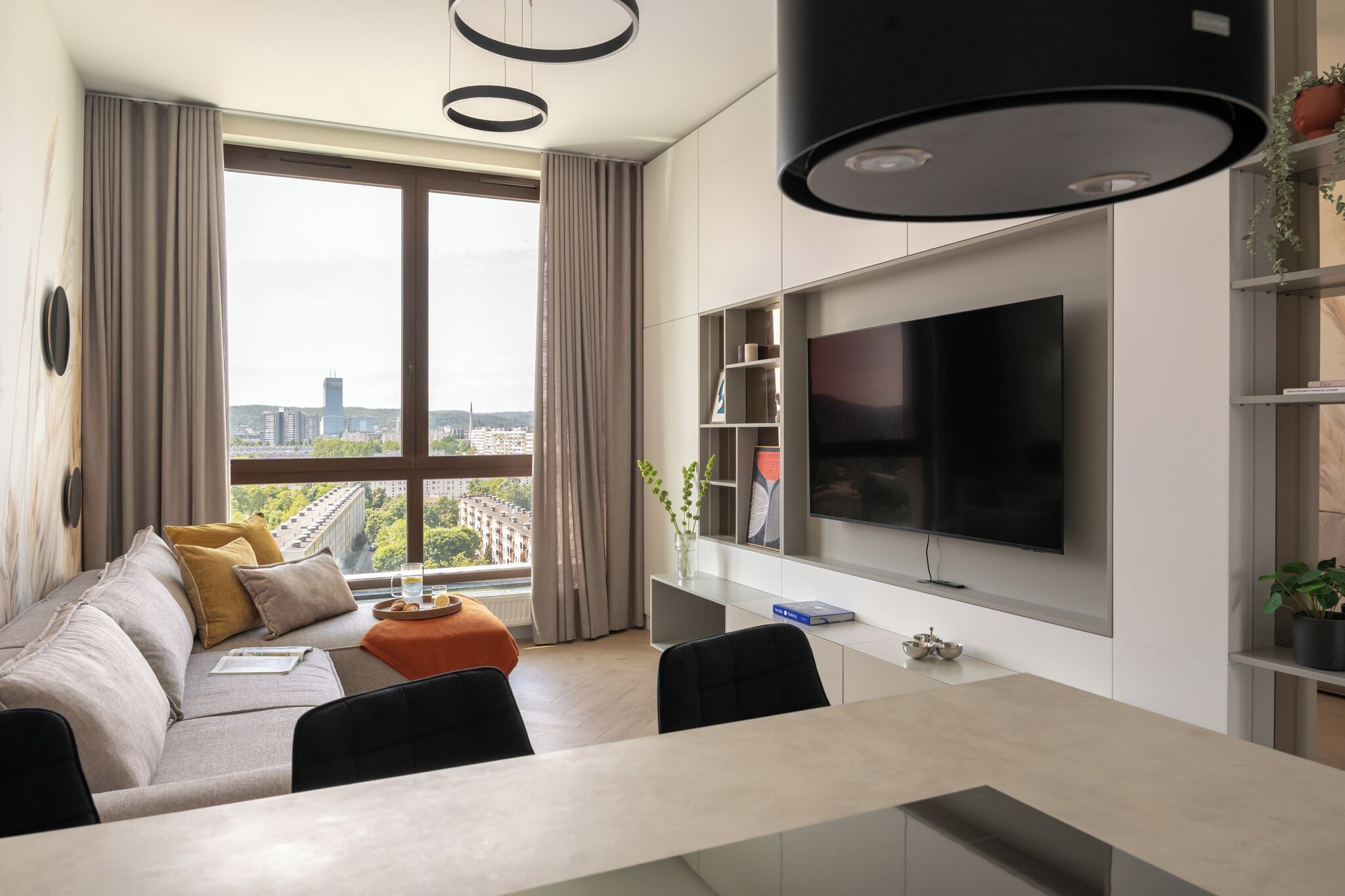 A modern living room with a sofa, dining table, and a large TV.