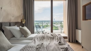 Ein modernes Schlafzimmer mit einem großen Bett, einem Balkon mit Blick auf die Stadt und einem Sessel.
