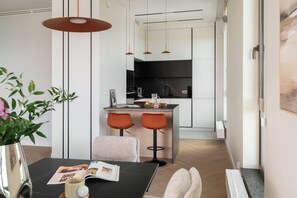 A modern kitchen with a central island, pendant lighting, and a dining area with a table and chairs. - Bulvar Penthouse Collection Gdańsk (Gdańsk)