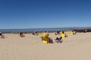 Een strand met gele strandhuisjes en mensen die ontspannen.