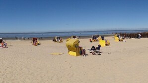 Una platja amb cabanes de bany de color groc i gent relaxant-se.