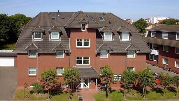 Un edifici residencial de diverses plantes amb façana simètrica, nombroses finestres i un accés central.