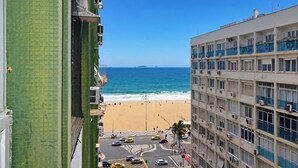 Blick aufs Meer von einem Hochhaus mit Strand und blauem Himmel.