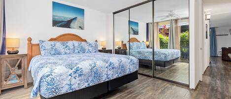 Un dormitorio con una cama grande, un ventilador de techo y un ventanal corredero que da a un balcón.