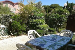 Eine Terrasse mit Tisch und Stühlen, umgeben von Pflanzen und einer Steinmauer.