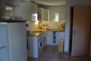 A compact kitchen with a washing machine, sink, and a small trash bin. - Le Clos d'Elsa N° 19 (Gruissan)