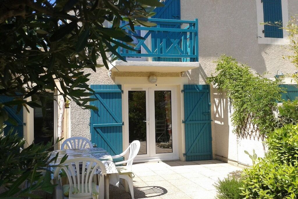 A building with a balcony, a table with chairs, and a door.