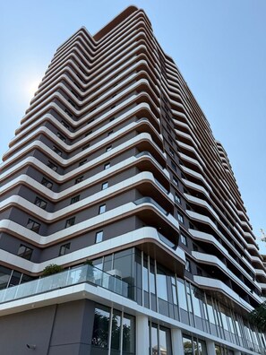 A modern high-rise building with a zigzag architectural design, featuring multiple balconies and large windows. - Luxe Residence, 2BR, Skopje Central, Riverside, Vodno View, AC (Skopje)