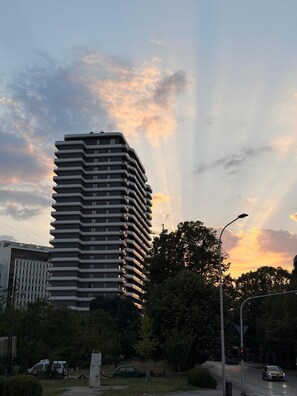 Ein hoch aufragendes Gebäude mit moderner Architektur, umgeben von Grünflächen und wolkenlosem Himmel.