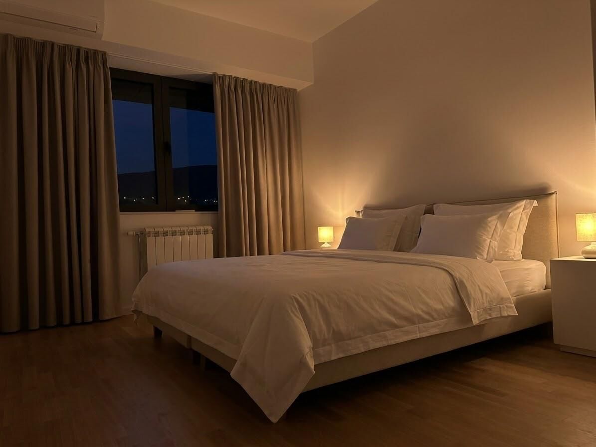 Hotellihuone, jossa on sänky, yöpöydät ja ikkuna, jossa on verhot.