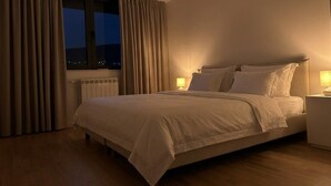 Een hotelkamer met een bed, nachtkastjes en een raam met gordijnen.