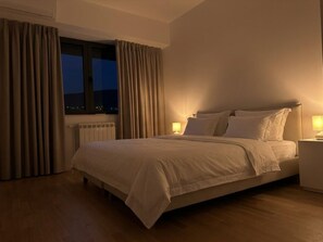 Ein Hotelzimmer mit einem Bett, Nachttischen und einem mit Vorhängen versehenen Fenster.