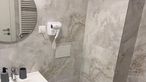 Een badkamer met een witte wastafel, toilet en een haardroger bevestigd aan de muur.