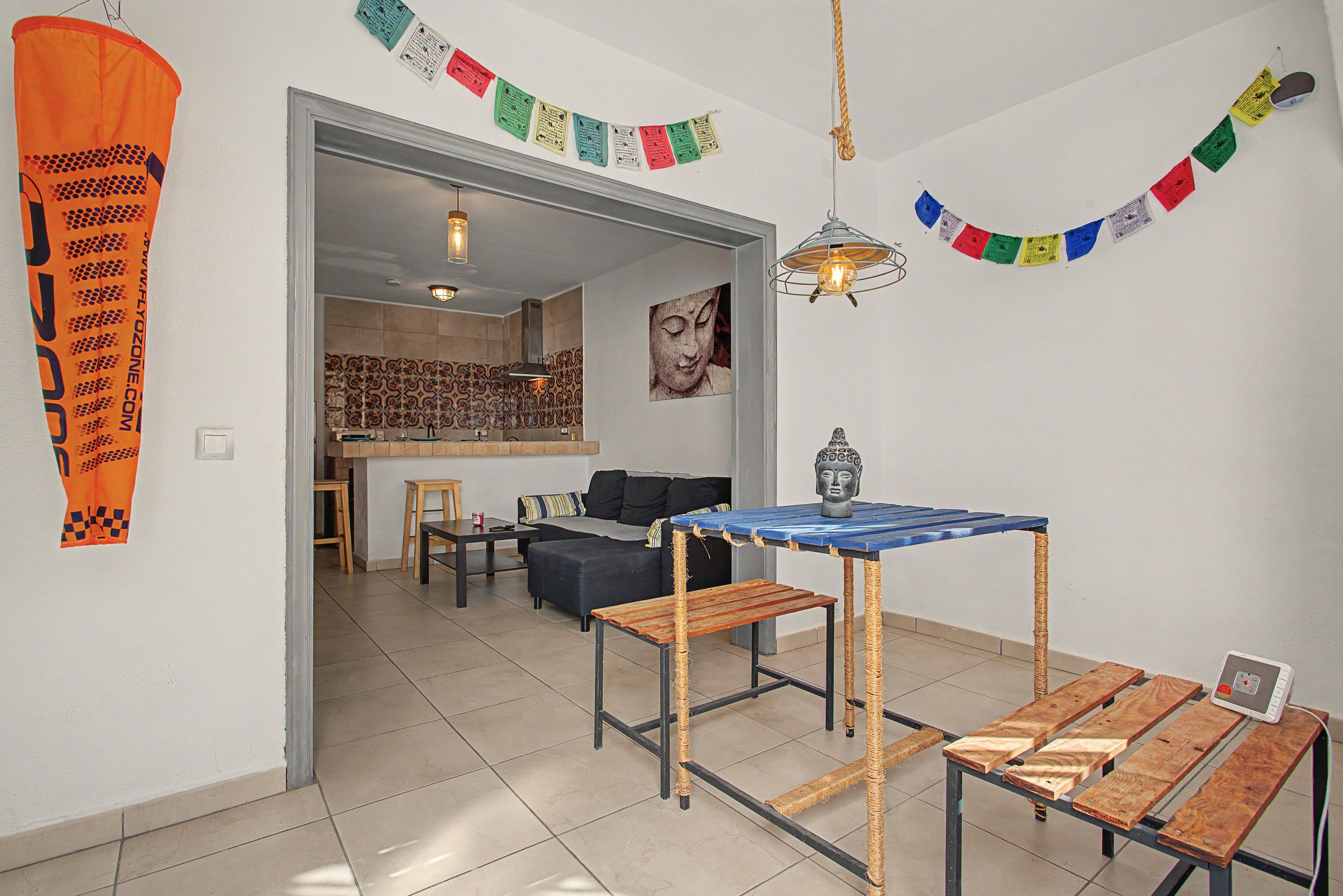 Ein modernes Wohnzimmer mit Essbereich, einer Couch, einem Tisch mit Buddha-Statue und einer im Hintergrund sichtbaren Küche.
