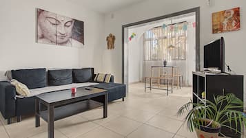 Un salon avec un canapé, une table basse et un téléviseur posé sur un meuble.
