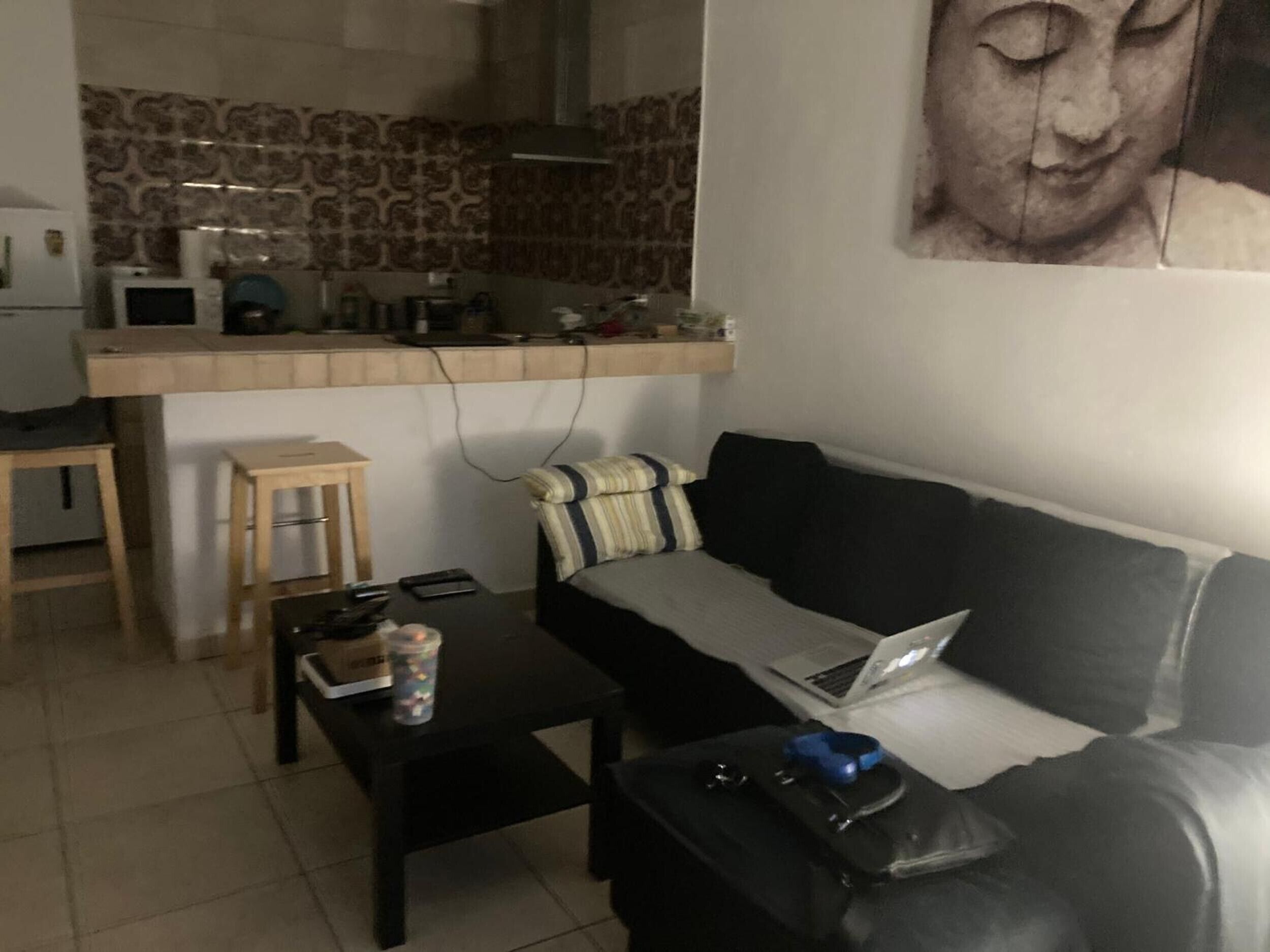 En stue med sofa, sofabord, en bærbar computer og et lille bord med en fjernbetjening.