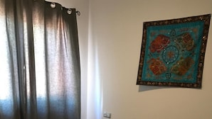 Tyypillinen hotellihuone, jossa on sänky, verhot ja seinälle ripustettu taideteos.