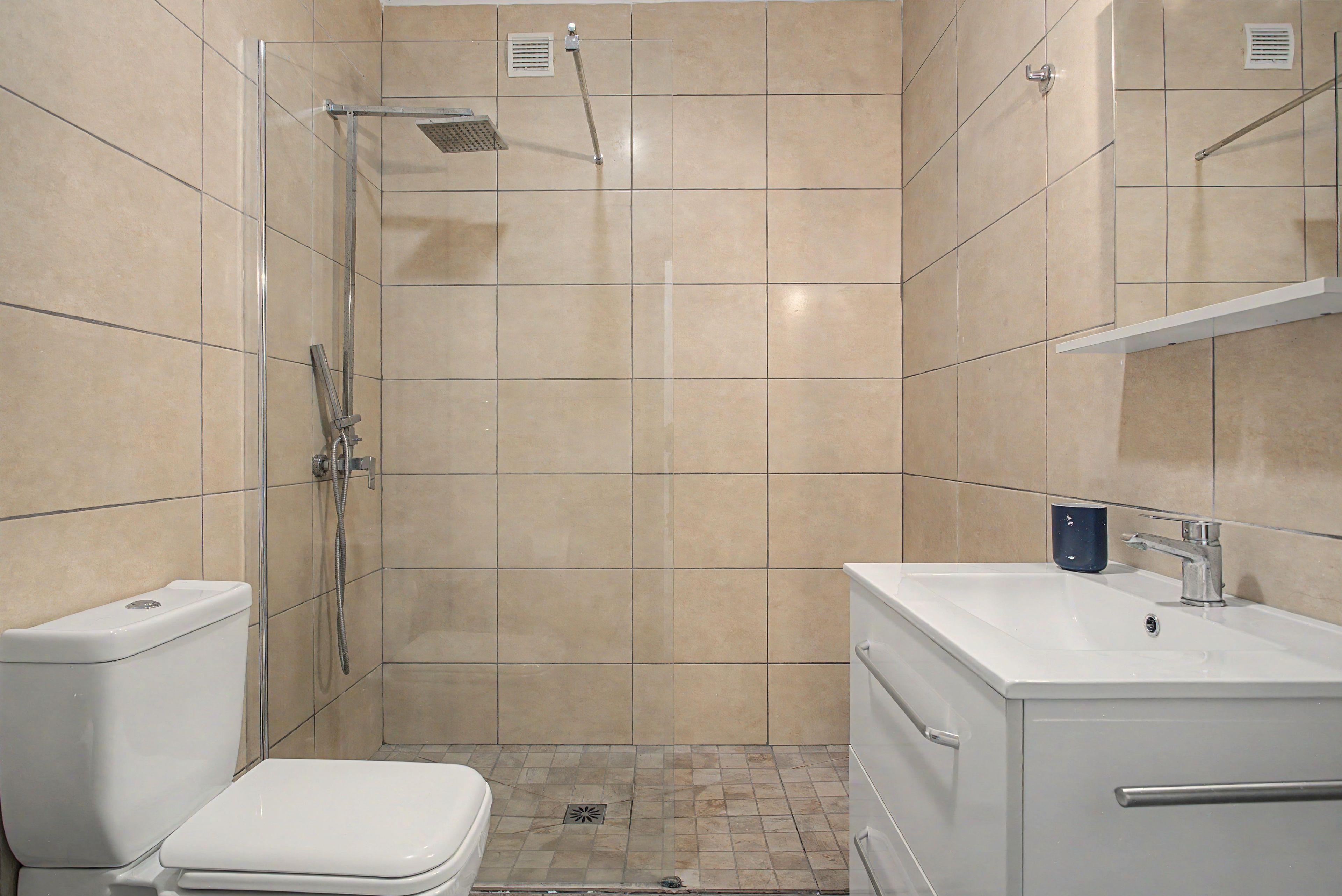 Een badkamer met douche, toilet en wastafel.