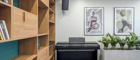 Un espace de bureau moderne avec un bureau noir, des étagères en bois et deux tableaux abstraits encadrés accrochés au mur.