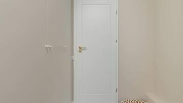 En vit dörr med ett mässingshandtag, en vit vägg och en mönstrad matta på golvet.