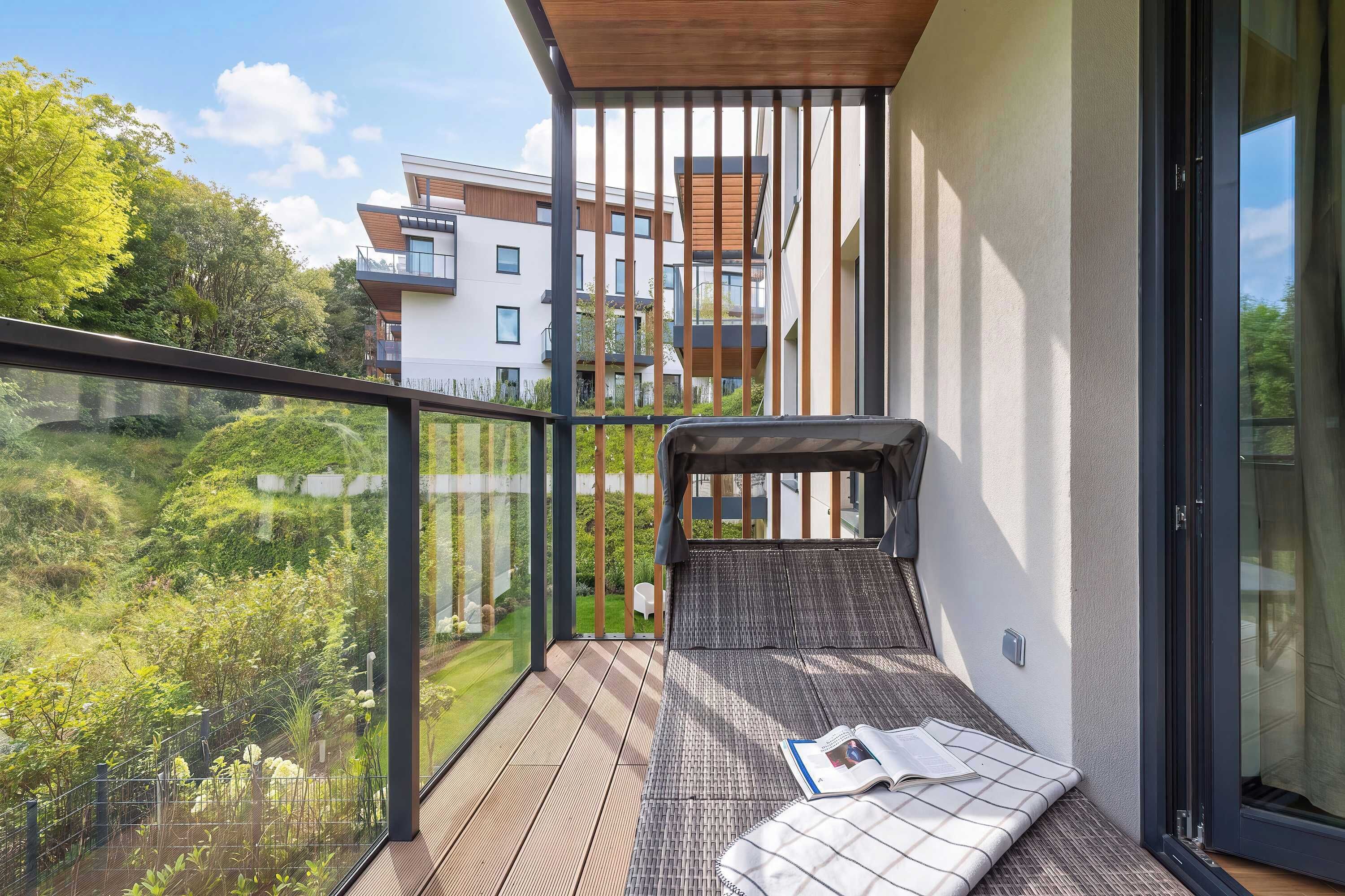 A balcony with a view of a residential area, a wooden floor, and a cushion with a book.