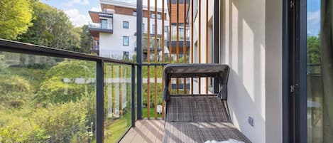 A balcony with a view of a residential area, a wooden floor, and a cushion with a book.