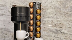 A Nespresso coffee machine with a cup and a coffee pod holder on a marble countertop. - Morehead City House - Loft - One bedroom suite with full kitchen and living area (Morehead City)